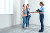 a woman and her female partner stand in a room with a man